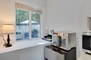 A kitchenette with a built-in oven, a lamp, and a window overlooking a patio area.