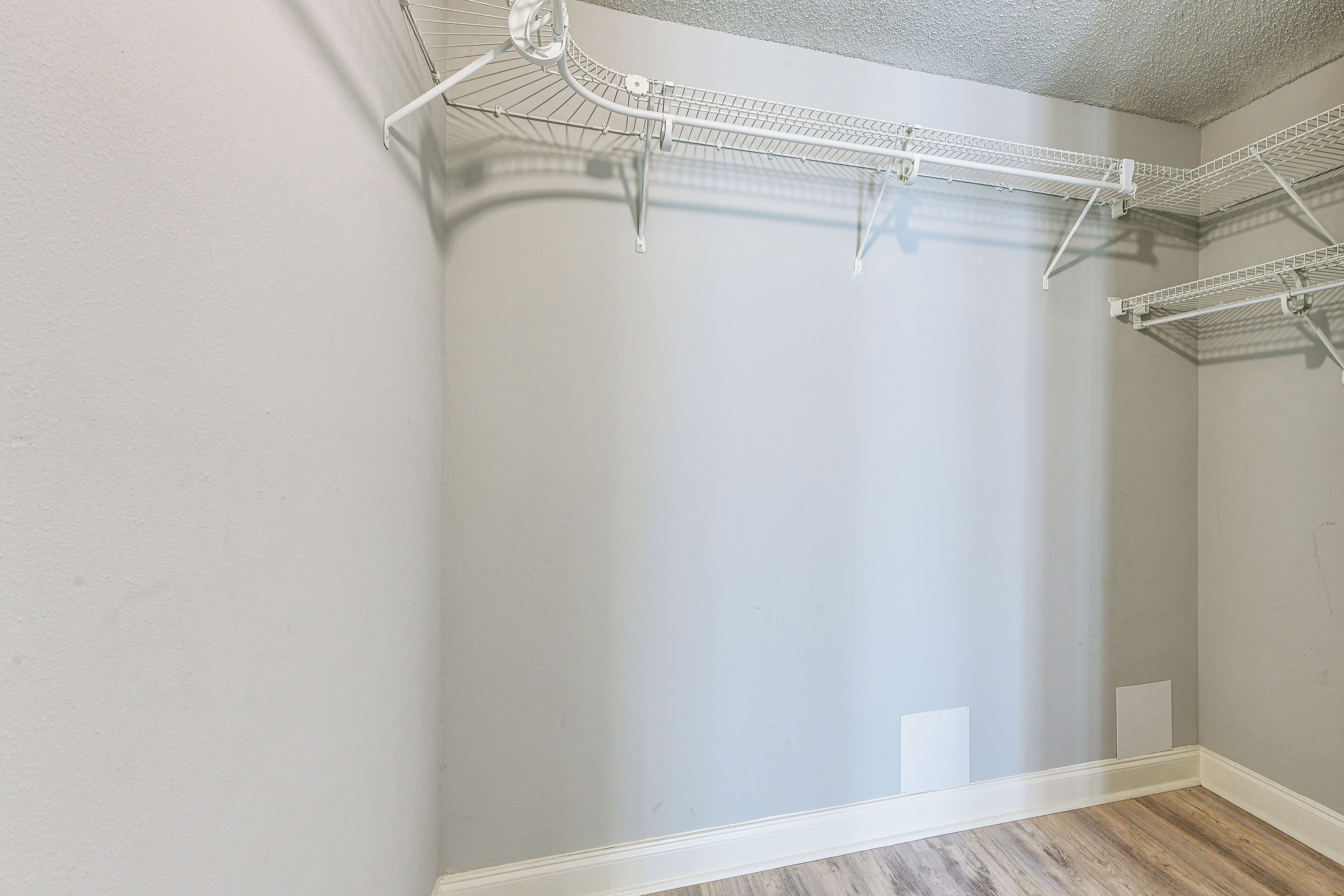 Een hoek van een kamer met een witte muur, een houten vloer en een wit plafond.