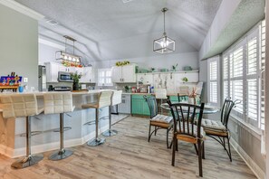 A kitchen with a bar area, green cabinets, and a dining table with chairs. - Private Yard & Patios: Family Home in Laplace! (LaPlace)