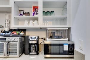 A kitchenette with a coffee maker, microwave, and storage cabinets.