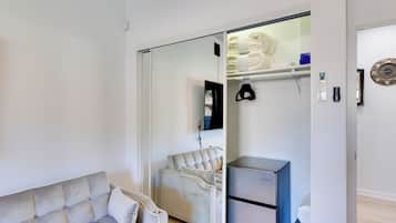 A modern living room with a sofa, a chair, a refrigerator, and a sliding glass door leading to a bathroom.