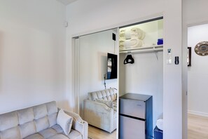 Uma sala de estar moderna com sofá, poltrona, geladeira e porta de vidro deslizante que dá para um banheiro.