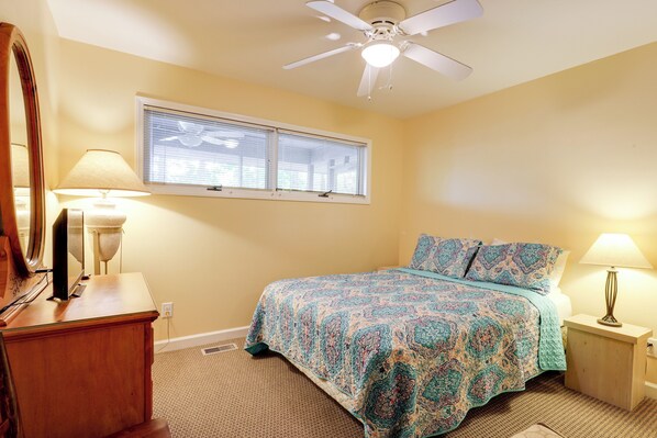 A bedroom with a bed, two bedside lamps, a ceiling fan, a window with blinds, and a wooden dresser. - Dock, Views & Fire Pit: Retreat on Lake Norman (Denver)