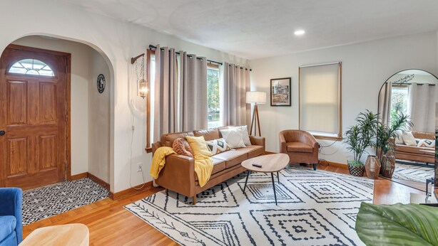 A living room with a brown sofa, a blue armchair, a coffee table, and a patterned rug. - 1 Mi to Dtwn Burlington: Modern Home w/ Yard! (Burlington)
