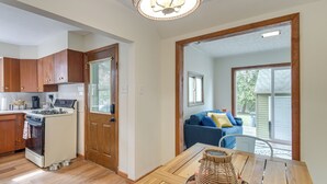 A kitchen with wooden cabinets, a stove, and a dining area with a table and chairs. - 1 Mi to Dtwn Burlington: Modern Home w/ Yard! (Burlington)