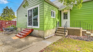 A green single-story house with a front porch, a small table and chairs, and a red staircase. - 1 Mi to Dtwn Burlington: Modern Home w/ Yard! (Burlington)