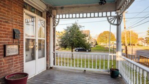 A porch with a white railing, a brick wall, and a potted plant.