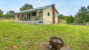A single-story house with a porch, a chimney, and a fenced yard. - Dog-friendly Cabin w/ Yard Near Auxvasse Creek! (Kingdom City)