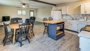A spacious kitchen with a dining area, wooden flooring, and white cabinets. - Dog-friendly Cabin w/ Yard Near Auxvasse Creek! (Kingdom City)