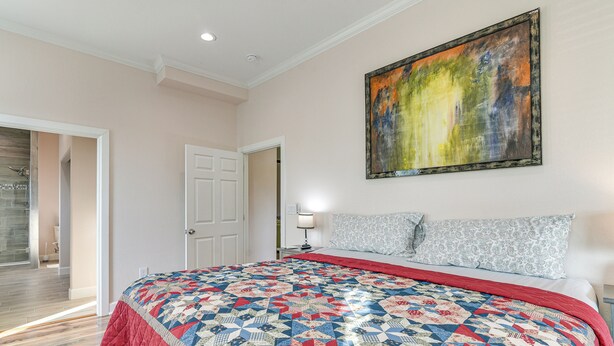 Un dormitorio con una cama grande, un cuadro en la pared y una puerta que da a otra habitación.