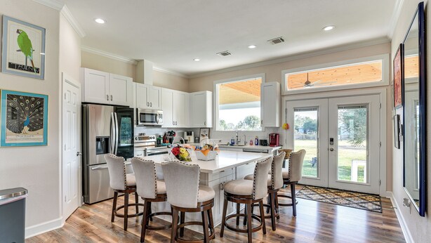 A modern kitchen with white cabinets, stainless steel appliances, and a central island with bar stools. - Farm Animals On-site: Needville Ranch Getaway! (Needville)