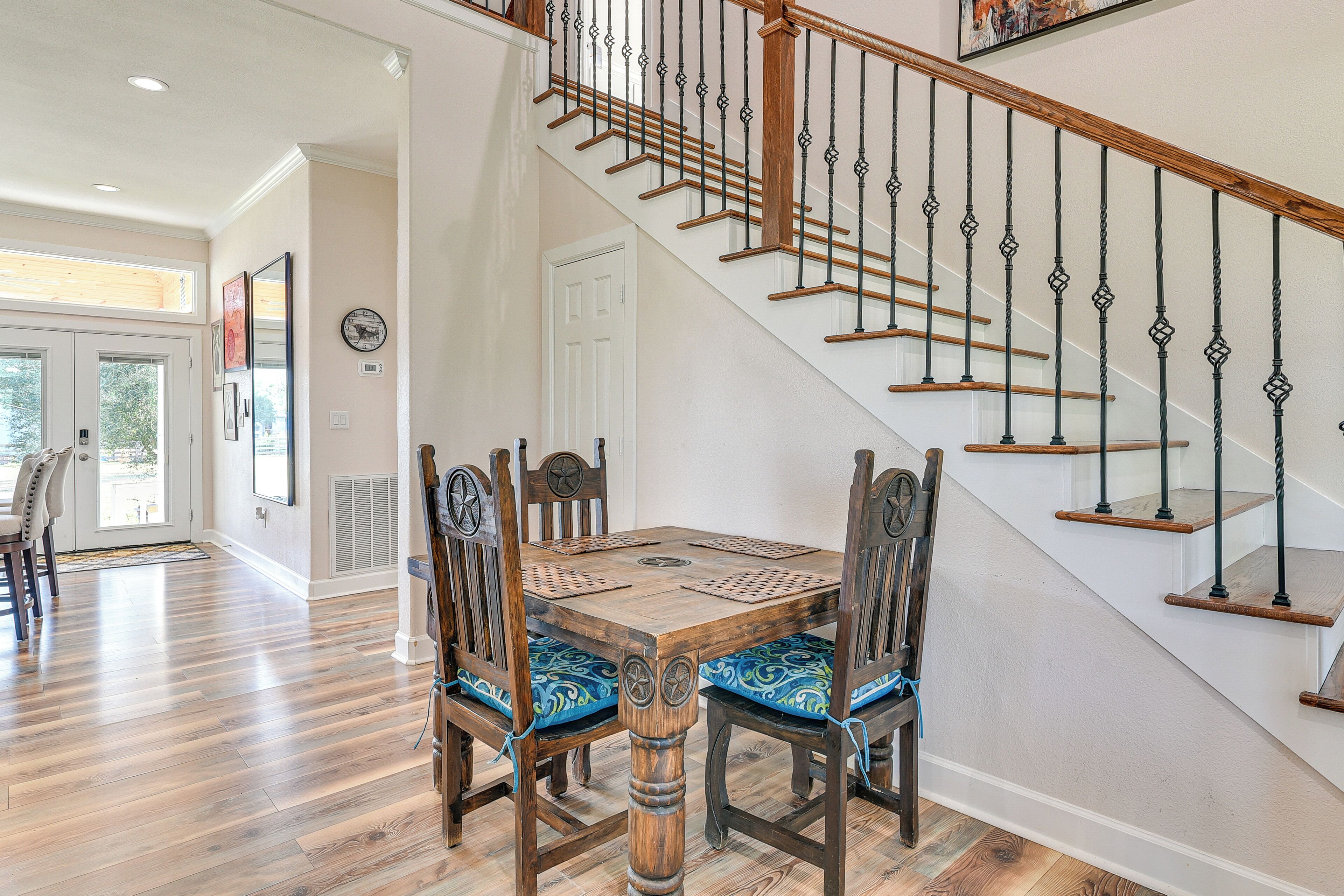 A dining area with a wooden table and chairs, a staircase with a wooden railing, and a door leading to another room.