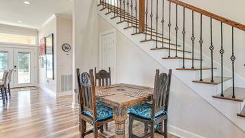 A dining area with a wooden table and chairs, a staircase with a wooden railing, and a door leading to another room.