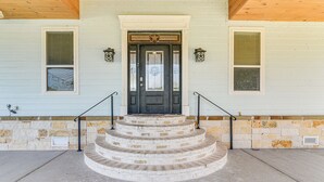 A two-story house with a front porch, a set of stairs leading to the front door, and a stone foundation. - Farm Animals On-site: Needville Ranch Getaway! (Needville)