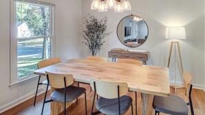 A dining area with a wooden table and chairs, a chandelier, a mirror, and a lamp. - 19 Mi to Kansas City: Group Retreat w/ Game Room! (Blue Springs)