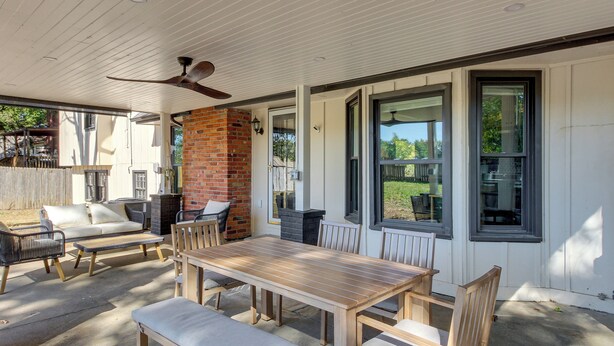 A covered patio with a wooden table and chairs, a sofa, and a ceiling fan. - 19 Mi to Kansas City: Group Retreat w/ Game Room! (Blue Springs)