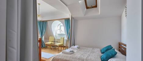 Un dormitorio con cama, una silla, una mesa y una ventana.