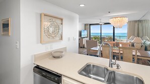 A modern kitchen with a dishwasher, a sink, and a dining area with a view of the ocean. - Gulf Front - Unsurpassable Views - Pool - Workout Room - Private Beach Access (Santa Rosa Beach)