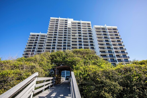 A multi-story building with a central staircase leading to an entrance, surrounded by dense greenery. - Gulf Front - Unsurpassable Views - Pool - Workout Room - Private Beach Access (Santa Rosa Beach)