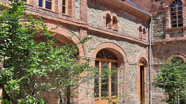 A historic building with arched windows and a central wooden door, surrounded by greenery. - Ab 1 Person: Rittergut mit Kamin, Fasssauna und mehr Nähe Sächsische Schweiz Dresden (Großharthau)