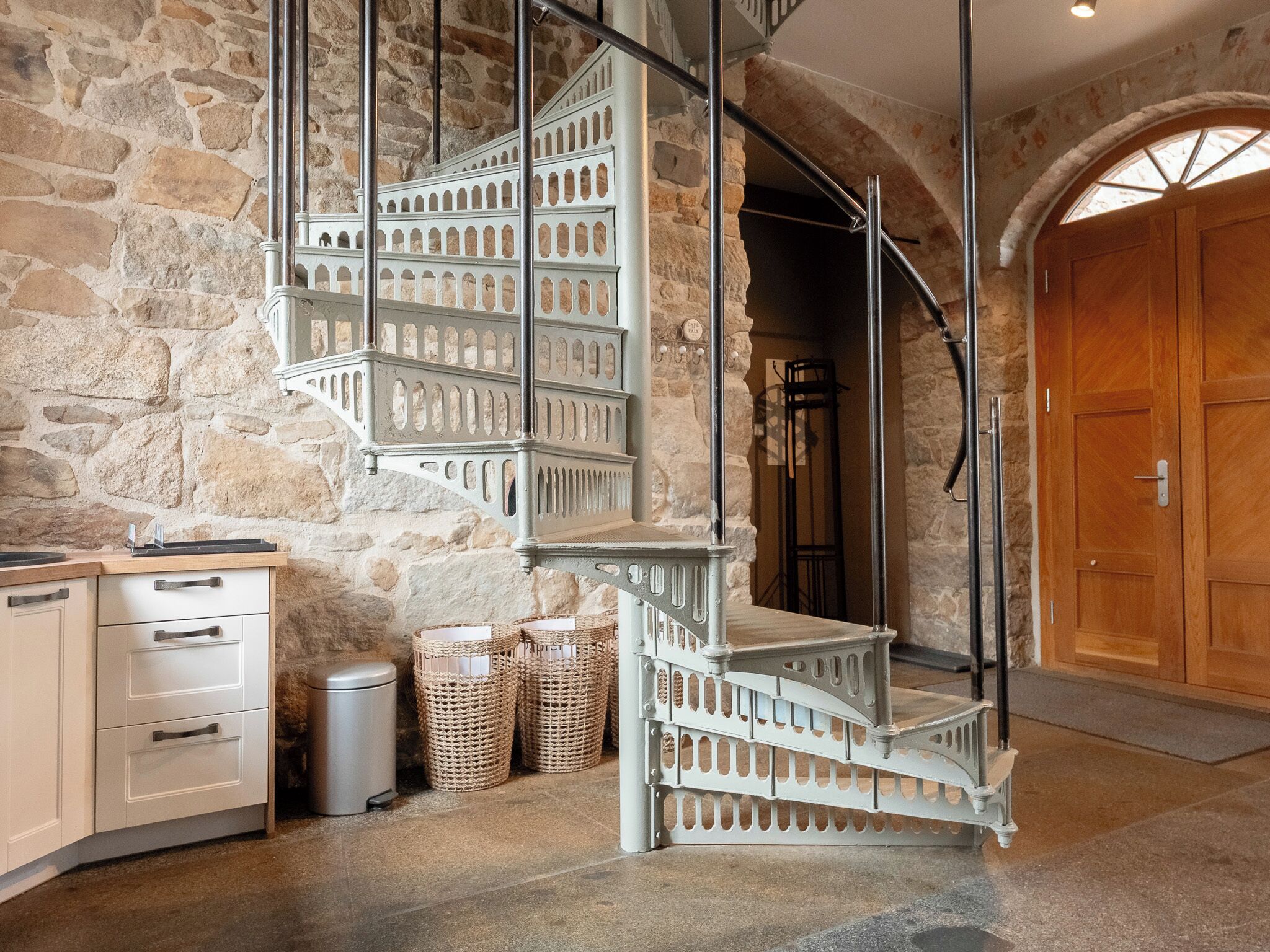 A spiral staircase with metal railings in a stone-walled room.