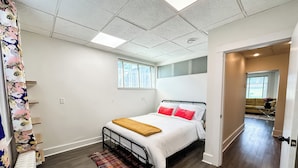 A bedroom with a bed, a window, and a door leading to another room.