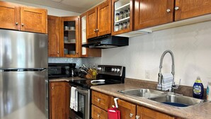 A modern kitchen with wooden cabinets, stainless steel appliances, a double sink, and a microwave.