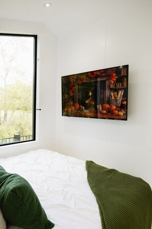 A bedroom with a bed, a window, and a wall-mounted painting.