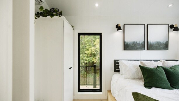 A bedroom with a bed, a window, and two wall-mounted picture frames.