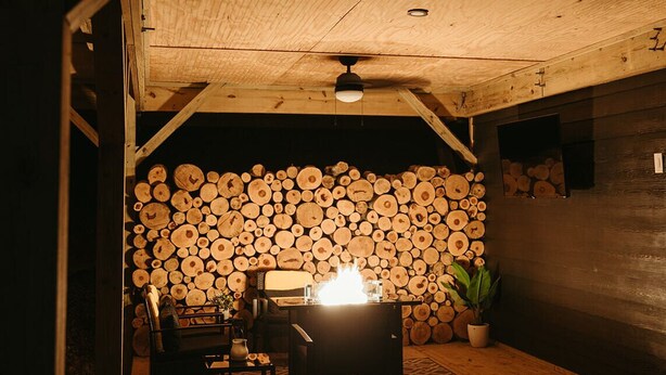 Une pièce chaleureuse avec un plafond en bois, une cheminée, une table à manger et une chaise.