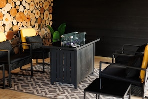 Een moderne bar met een glazen toonbank, zwarte meubels en een wand versierd met houtblokken.