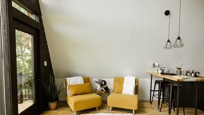 Un loft moderne avec deux fauteuils de couleur moutarde, une table à manger en bois et un tapis en fausse fourrure blanche.