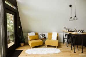 Un loft moderno con due poltrone color senape, un tavolo da pranzo in legno e una pelliccia sintetica bianca.