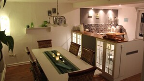 A dining area with a table, chairs, and a kitchen area with a counter and appliances. - Holiday Home 'Fachwerkhaus Korntenne' with Mountain View, Private Terrace and Wi-Fi (Willingen (Upland))