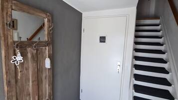 A wooden door with a mirror, a white door with a nameplate, and a staircase with black steps.