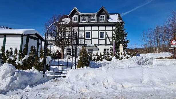 A large, traditional building with a symmetrical facade, a gated entrance, and snow-covered surroundings. - Holiday Home 'Fachwerkhaus Korntenne' with Mountain View, Private Terrace and Wi-Fi (Willingen (Upland))