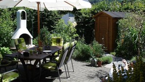 An outdoor patio with a table, chairs, and a pizza oven. - Holiday Home 'Fachwerkhaus Korntenne' with Mountain View, Private Terrace and Wi-Fi (Willingen (Upland))