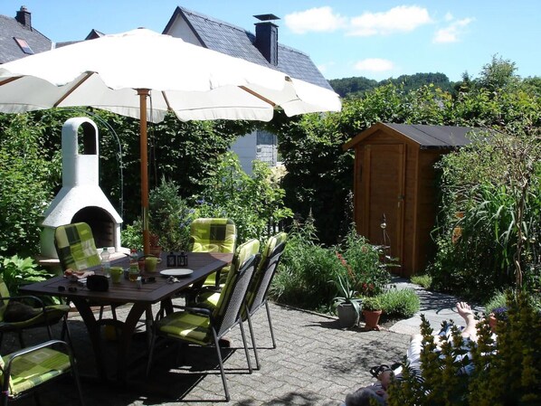 Une terrasse extérieure avec une table, des chaises et un four à pizza.