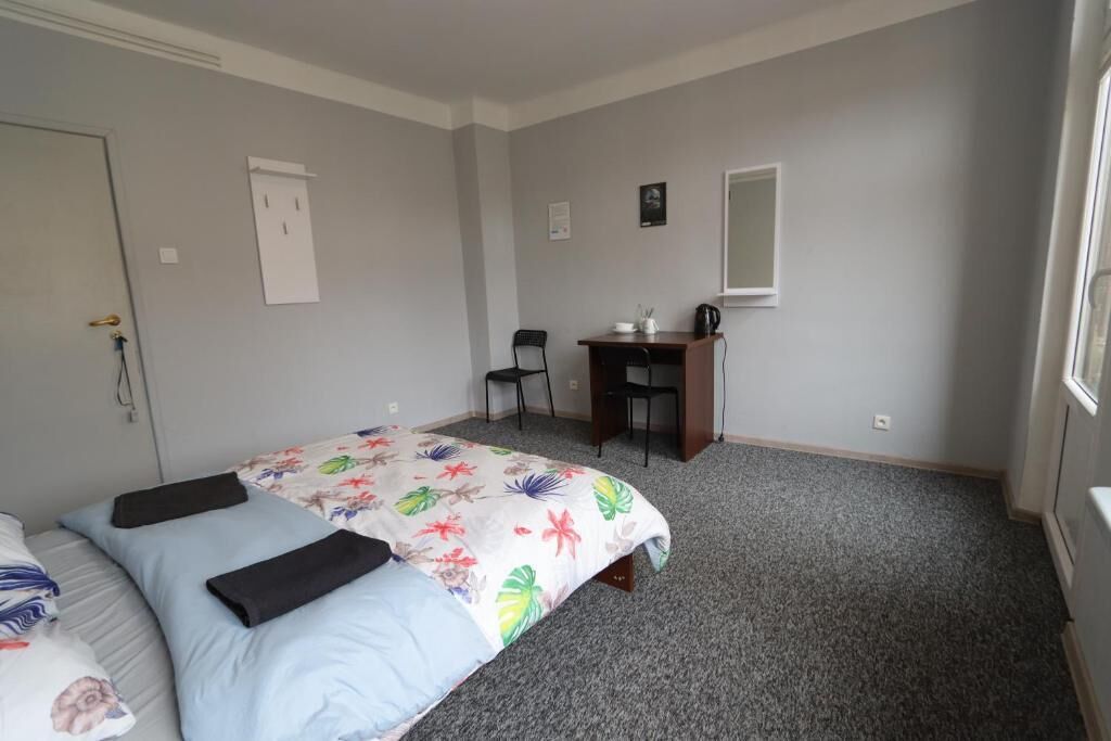 A bedroom with a bed, a desk, and a chair.
