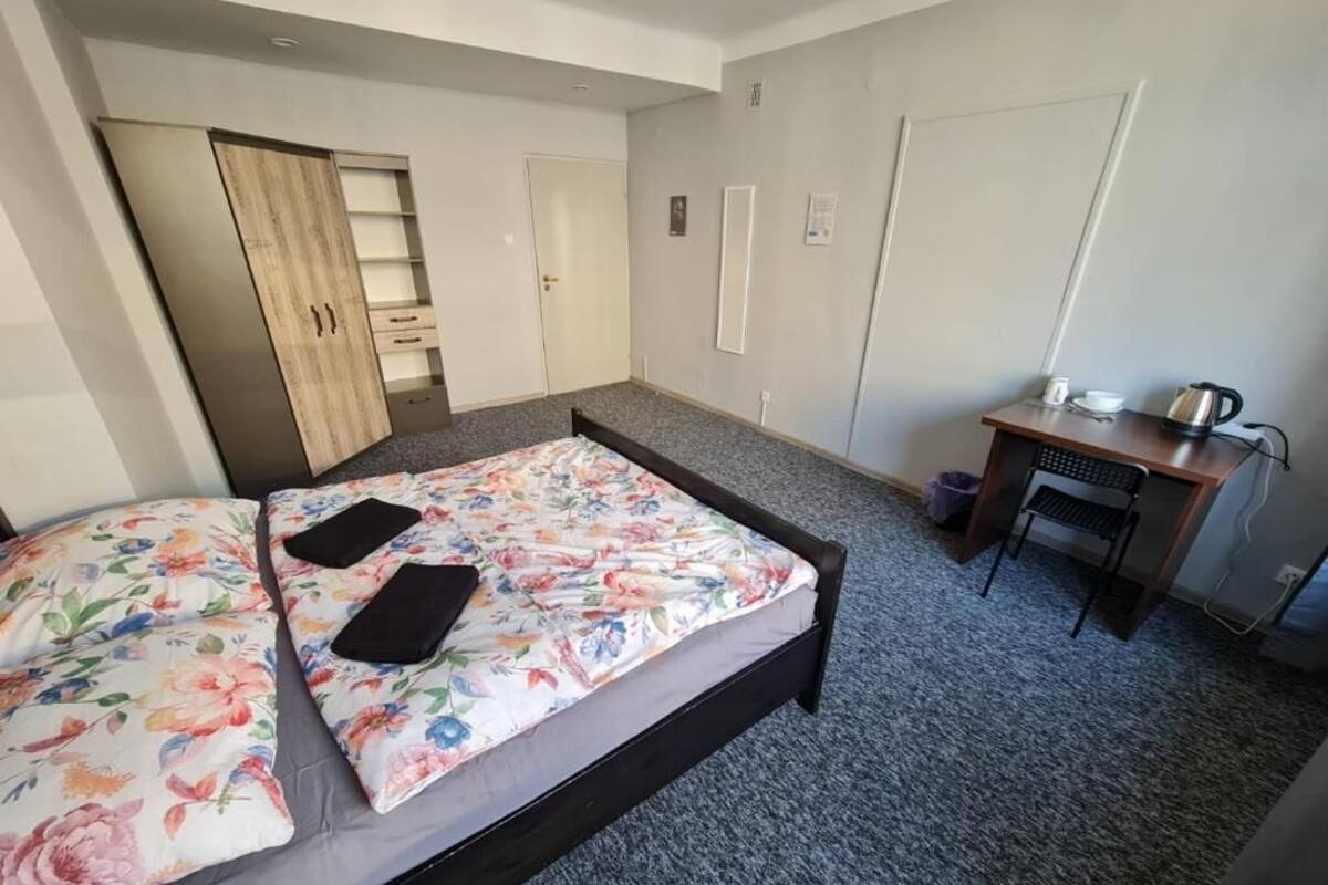 A bedroom with a bed, a desk, and a wardrobe.