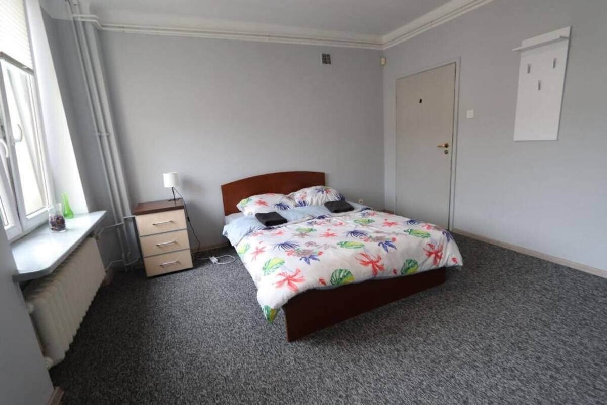 A bedroom with a bed, a desk, and a window.