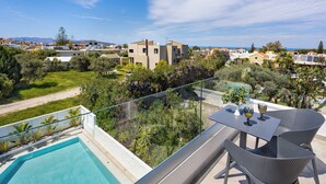 A balcony with a pool, outdoor seating, and a view of the surrounding area. - Sueno Studios and Apartments (Chania)