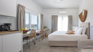 A modern hotel room with a bed, a desk, and a view of the city. - Sueno Studios and Apartments (Chania)