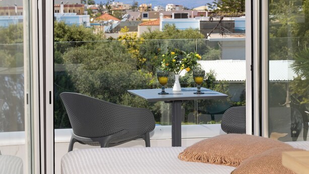 A balcony with a table, chairs, and a vase with flowers. - Sueno Studios and Apartments (Chania)