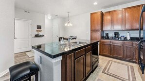 A modern kitchen with wooden cabinets, a granite countertop, and stainless steel appliances. - Ten Mile B-102 Ground floor 2 bedroom with private patio upscale modern interior (Granby)