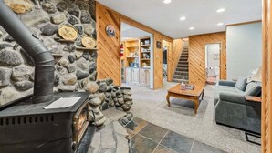 A cozy living room with a stone wall, a fireplace, a staircase, and a sofa. - 279 Shorewood Dr Grand Lake cabin getaway 3 bedroom, private HT, close to town (Grand Lake)