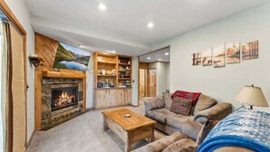 A cozy living room with a fireplace, a sofa, a coffee table, and a bookshelf. - 279 Shorewood Dr Grand Lake cabin getaway 3 bedroom, private HT, close to town (Grand Lake)