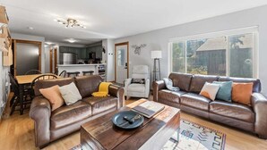 Una sala de estar moderna con dos sofás de cuero, una mesa de centro de madera y un comedor con una mesa y sillas de madera.