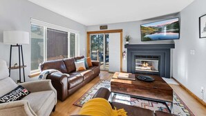 Una sala de estar moderna con chimenea, televisor grande y sofá.