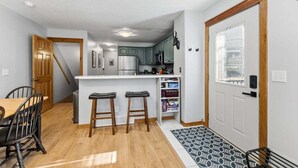 Una cocina moderna con una isla central, taburetes de bar y una mesa de comedor.